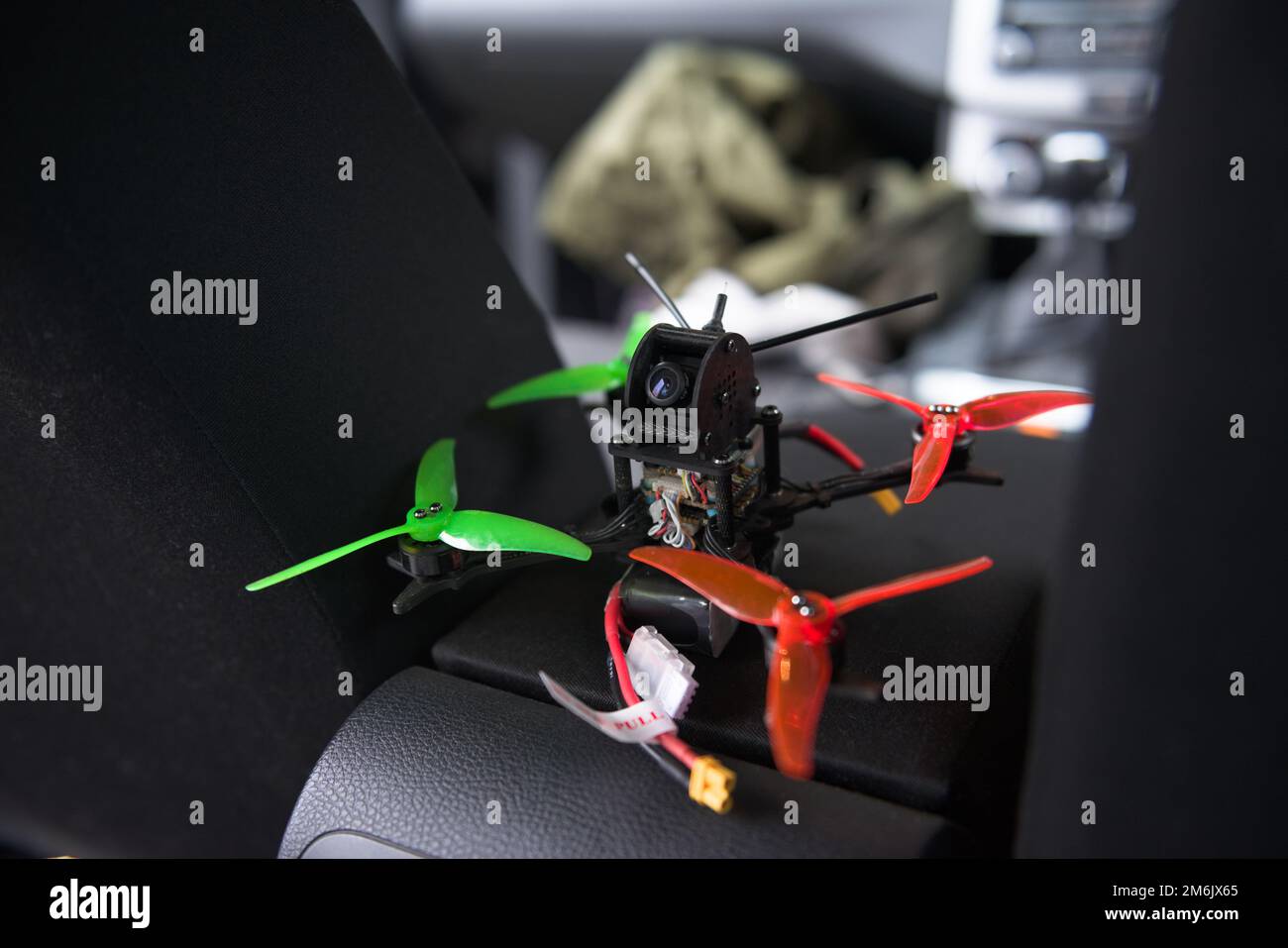 Close up selective focus image of small drone resting on a car armrest. Selective focus, with the remote first person view camera clearly visible. Stock Photo