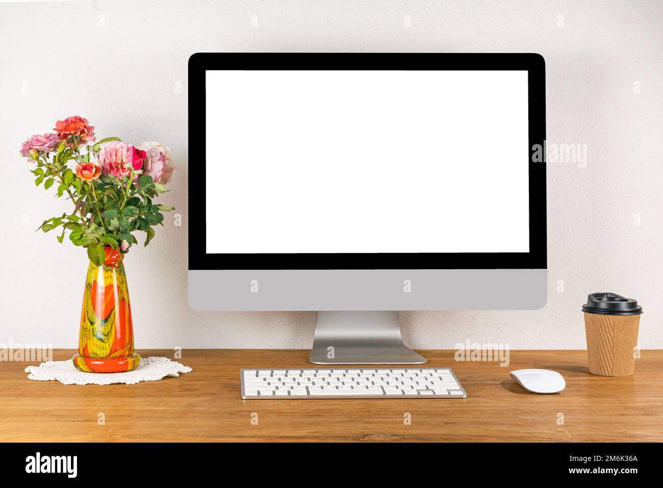 Blank screen desktop computer with wireless keyboard and mouse on wooden table. Stock Photo