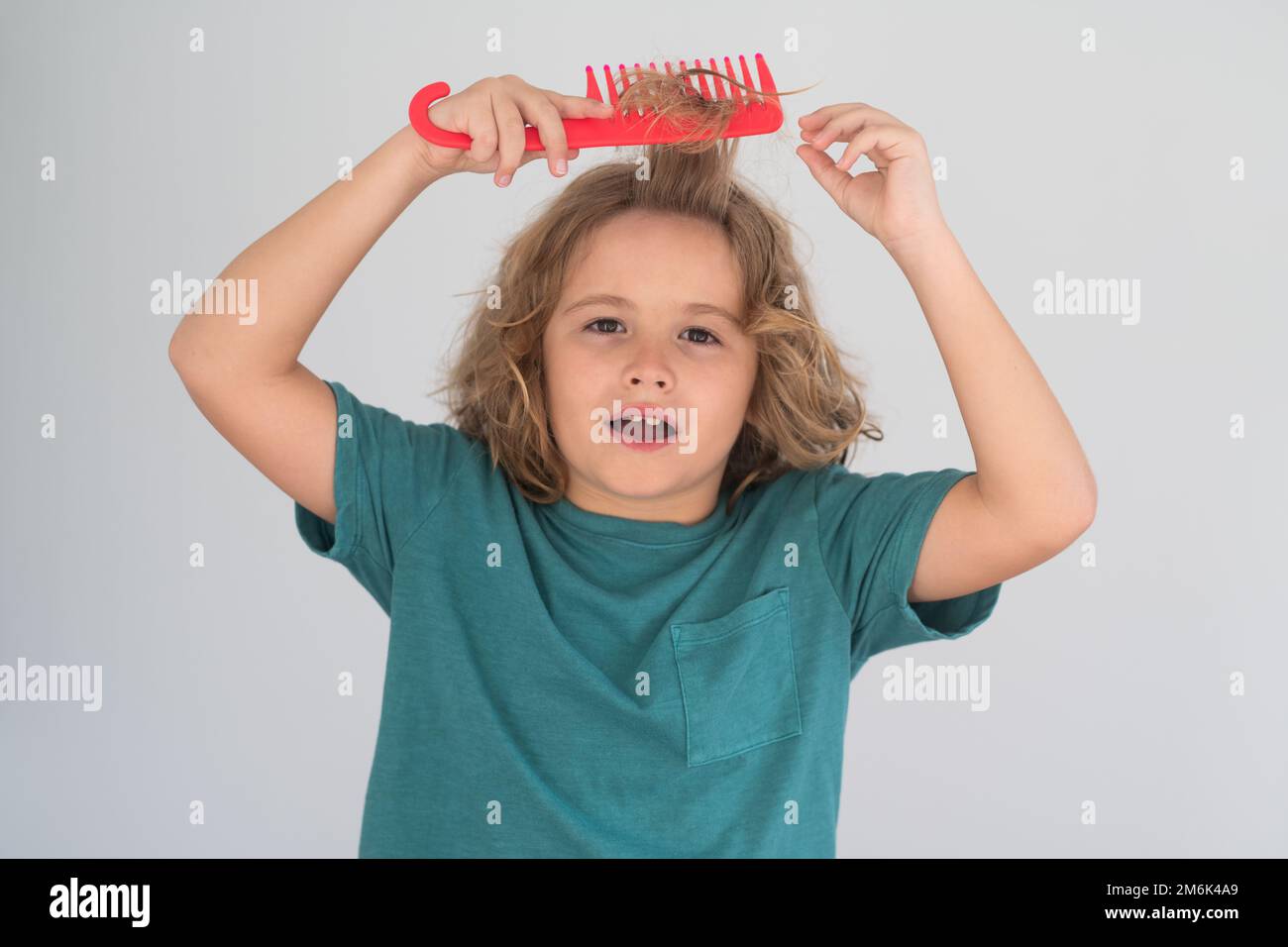 Kids hair. Funny child with curly blonde hair holding comb hairbrush
