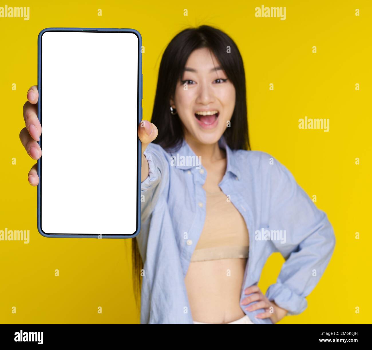 Young asian girl holding smartphone in hand showing white screen for
