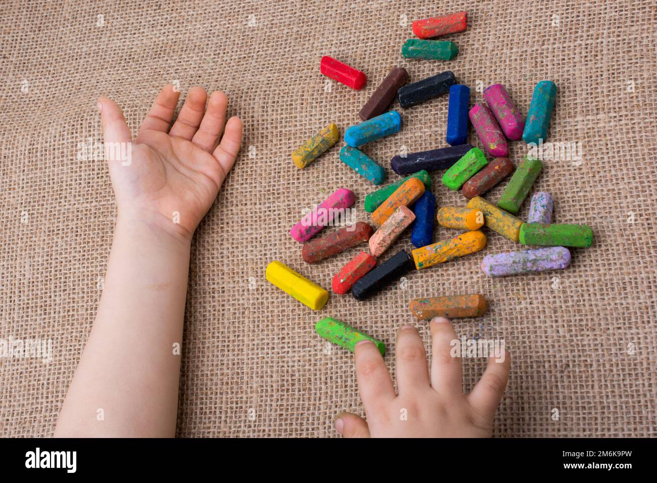 Used color crayons and a toddlers hand Stock Photo Alamy