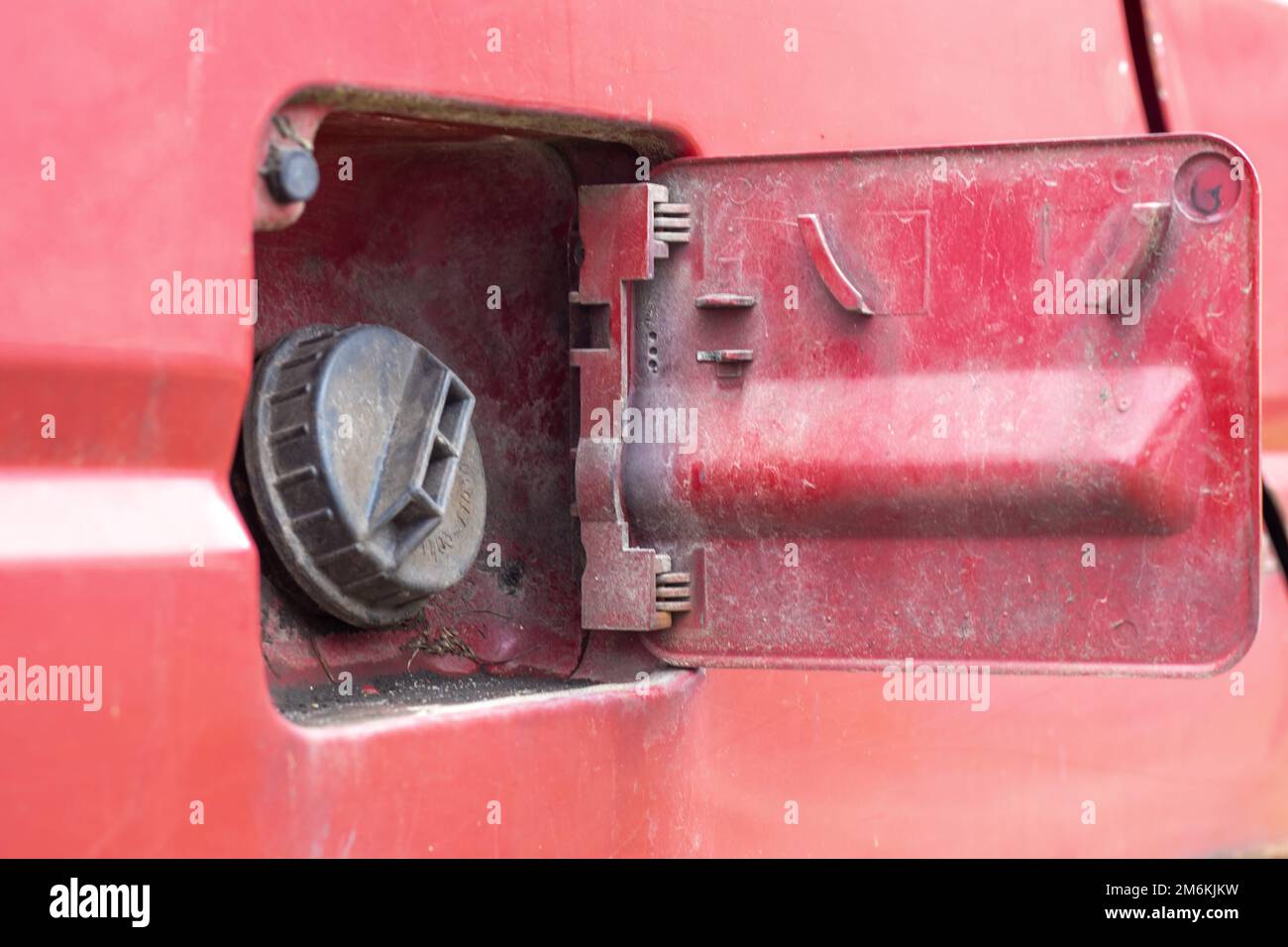 The car's open fuel tank cap was opened to pour gasoline or diesel fuel