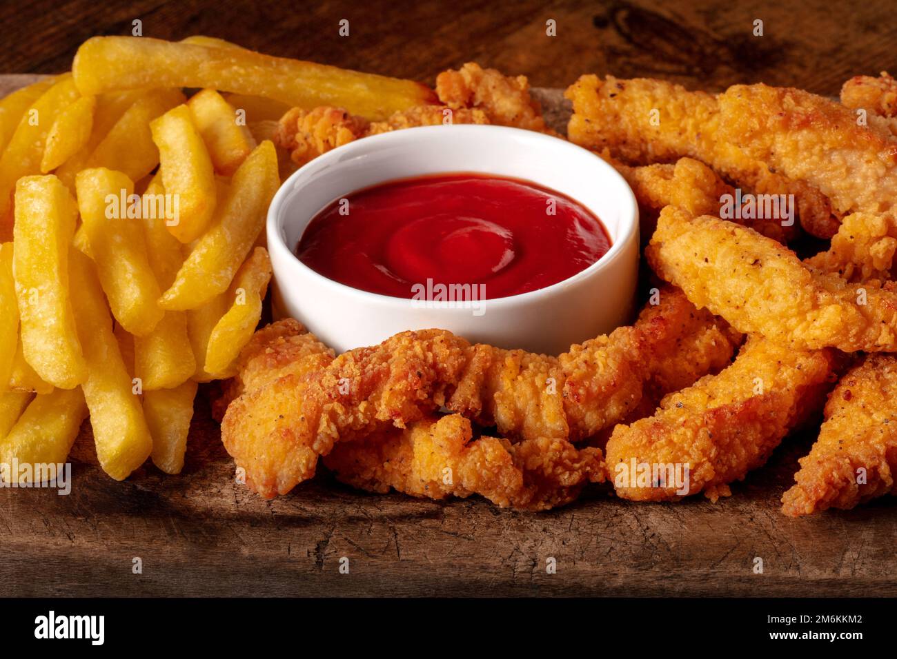 Chicken tenders, breaded and fried, with a red dip and French fries