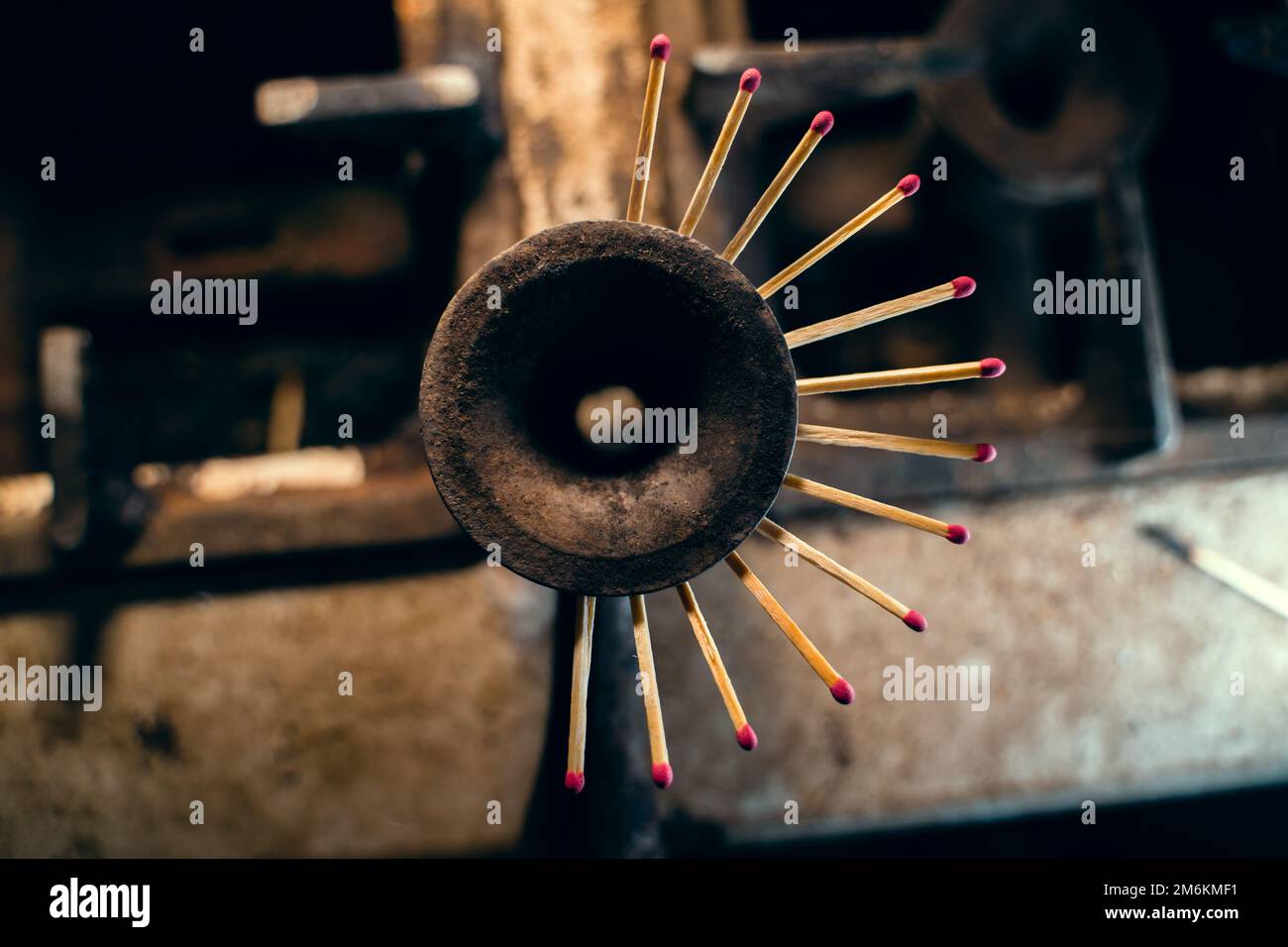 Gas burner of an old dirty kitchen stove with matches stuck in the jets