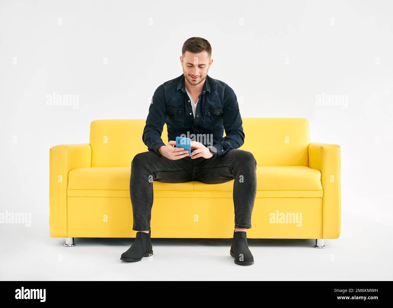Relaxed man sitting on couch using hsi mobile smart phone Stock Photo