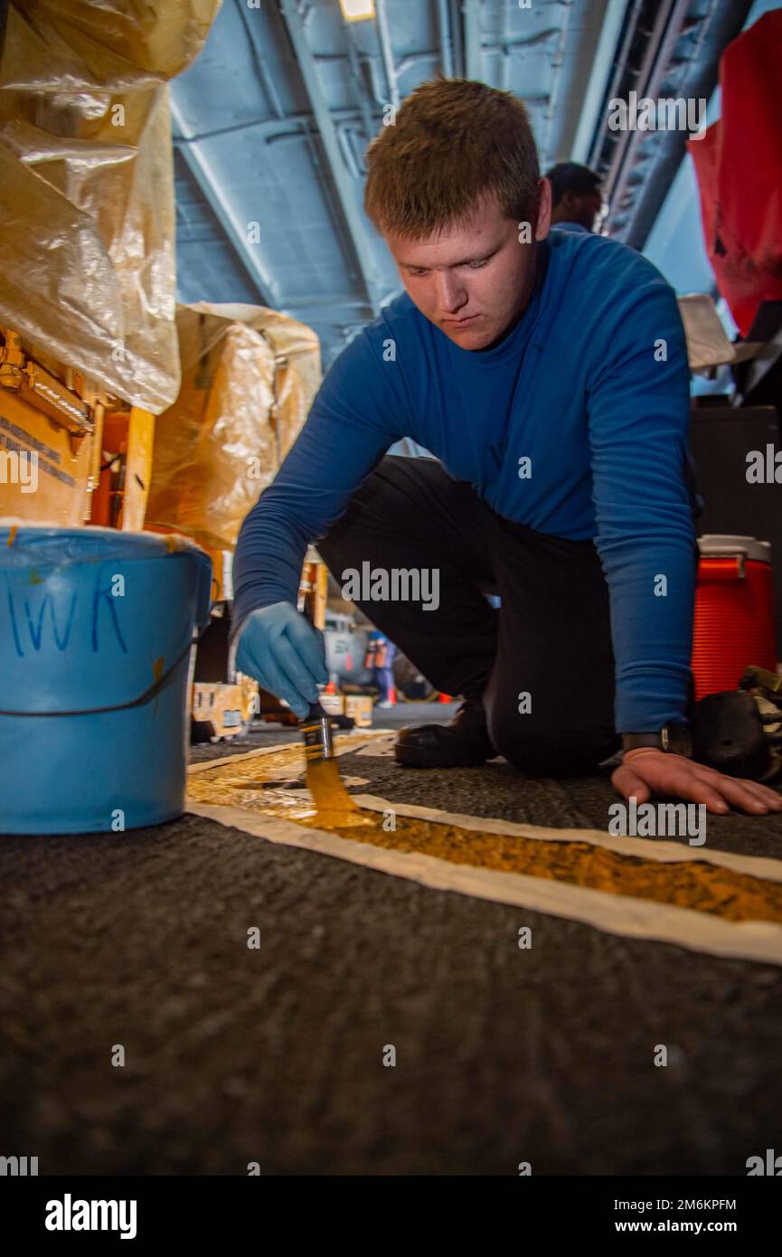 220430-N-BP862-1040 ADRIATIC SEA (April 30, 2022) Airman Christopher Tabor, from Arlington, Washington, paints a fire lane in the hangar bay of the Nimitz-class aircraft carrier USS Harry S. Truman (CVN 75), April 30, 2022. The Harry S. Truman Carrier Strike Group is on a scheduled deployment in the U.S. Sixth Fleet area of operations in support of U.S., allied and partner interests in Europe and Africa. Stock Photo