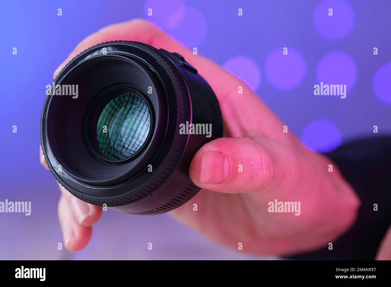 chinese 50mm lens in hand over table and colored background Stock Photo