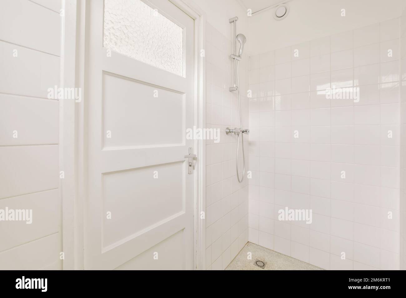 a bathroom with white tiles on the floor and shower stall door open to show how it's supposed to