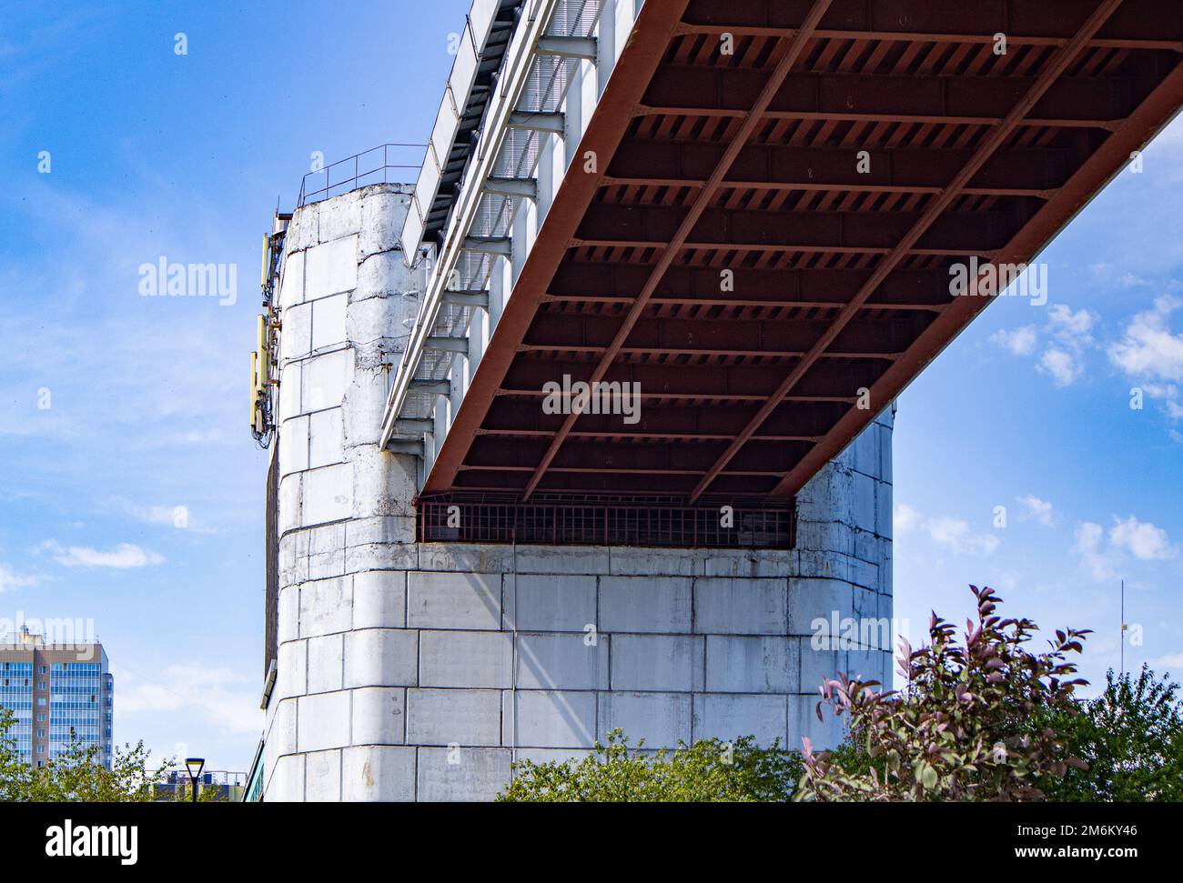 Engineering design of the metro bridge with concrete supports, bottom view. Panorama of the city with sky and trees Stock Photo