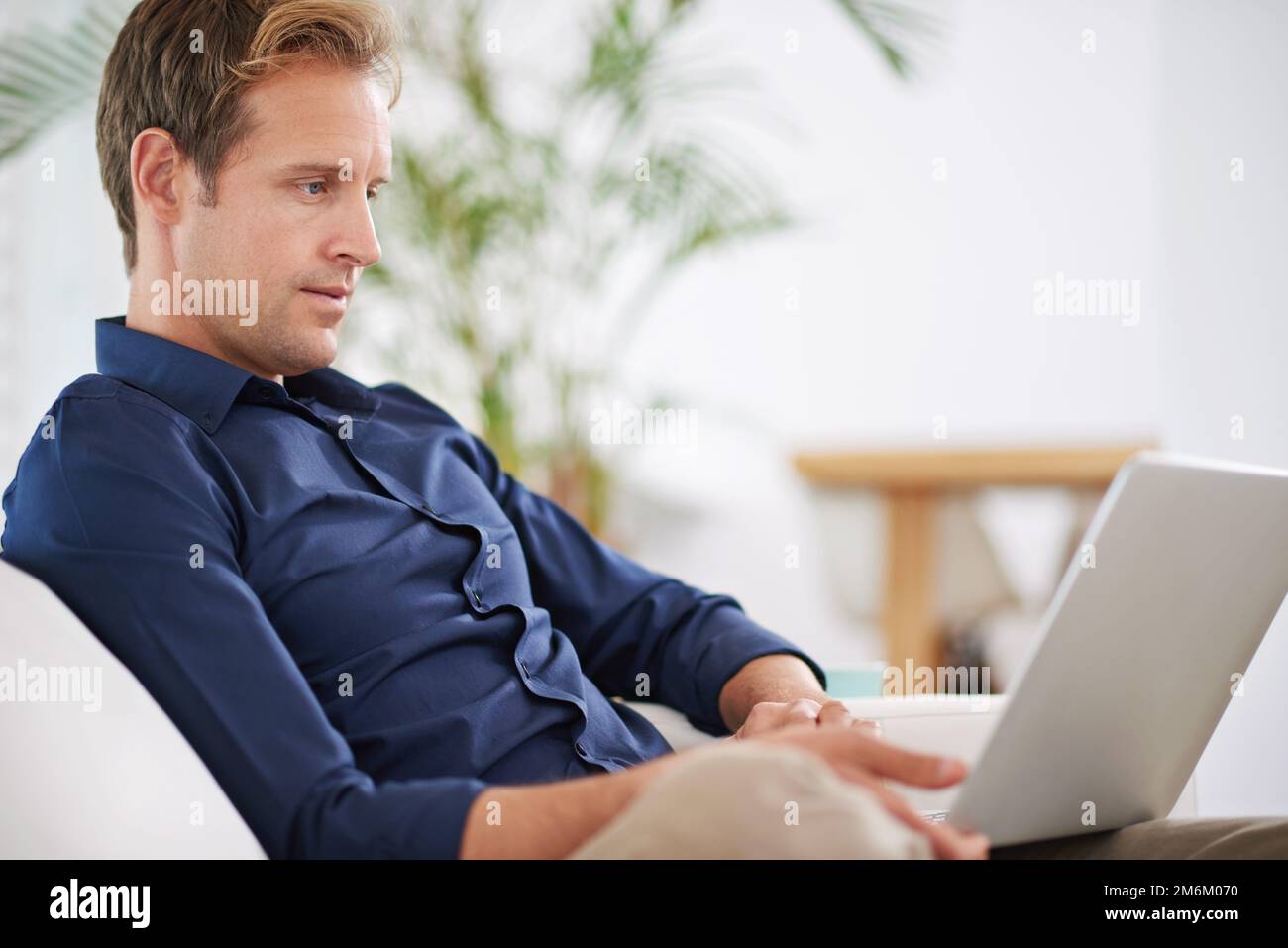 Taking a break from work. a handsome man relaxing at home with his laptop. Stock Photo