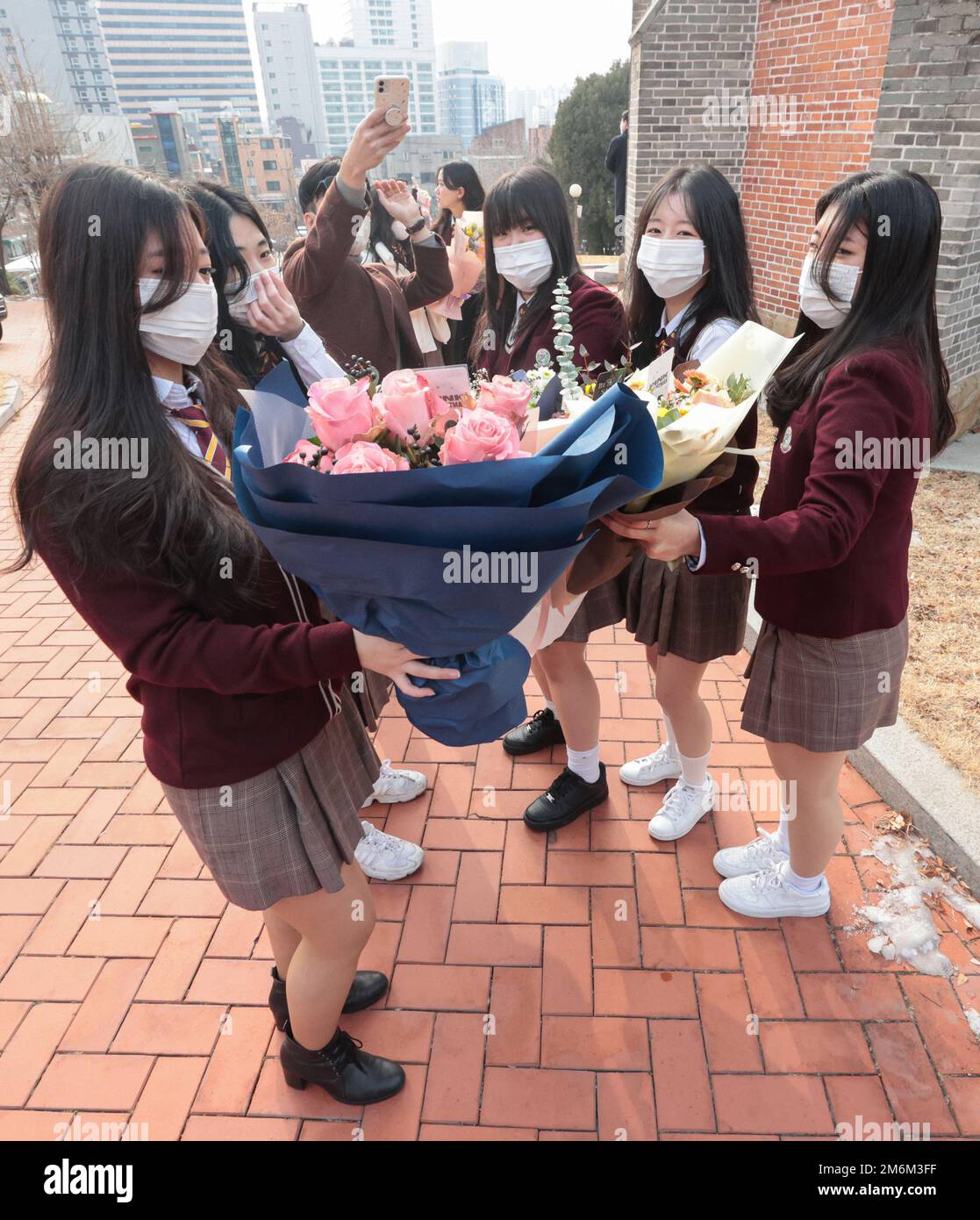 Graduation High school seniors holding bouquets pose for a group photo