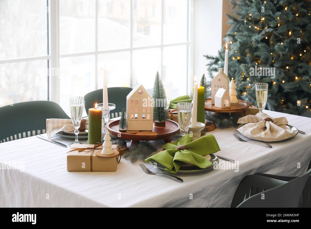 Christmas table setting with candle holders, presents and fir trees in ...