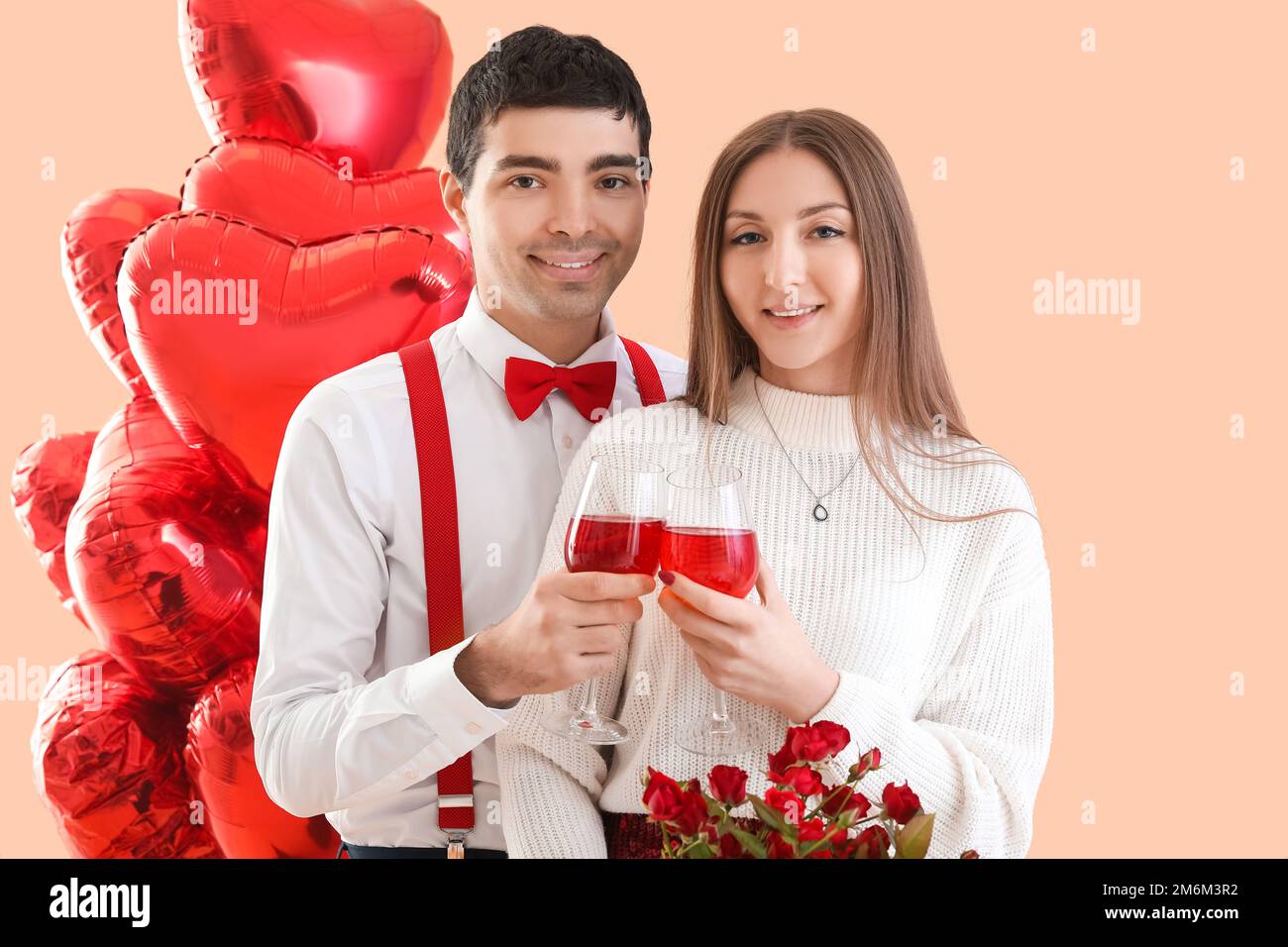 Young couple in love with glasses of wine on beige background ...