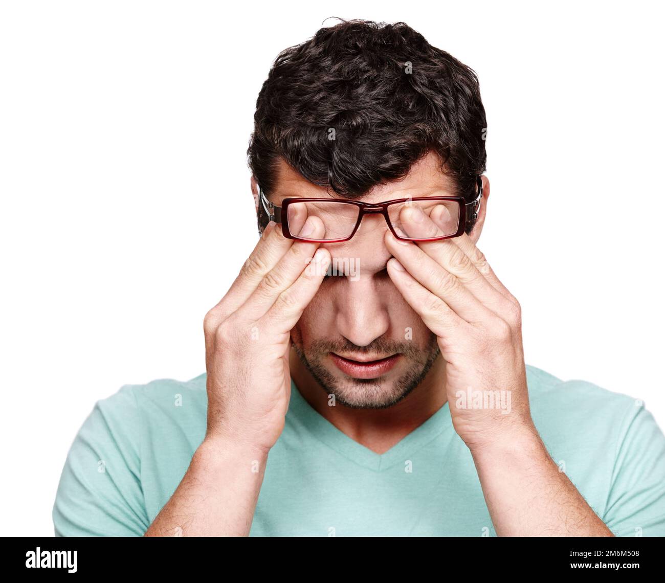 When will this headache end. A young man rubbing his forehead while isolated on a white background. Stock Photo