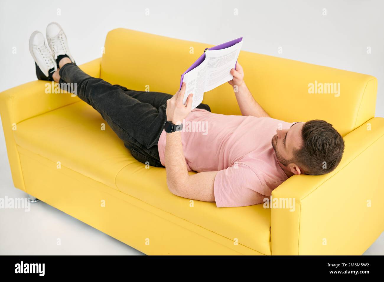 Man relaxing on sofa reading book Stock Photo Alamy