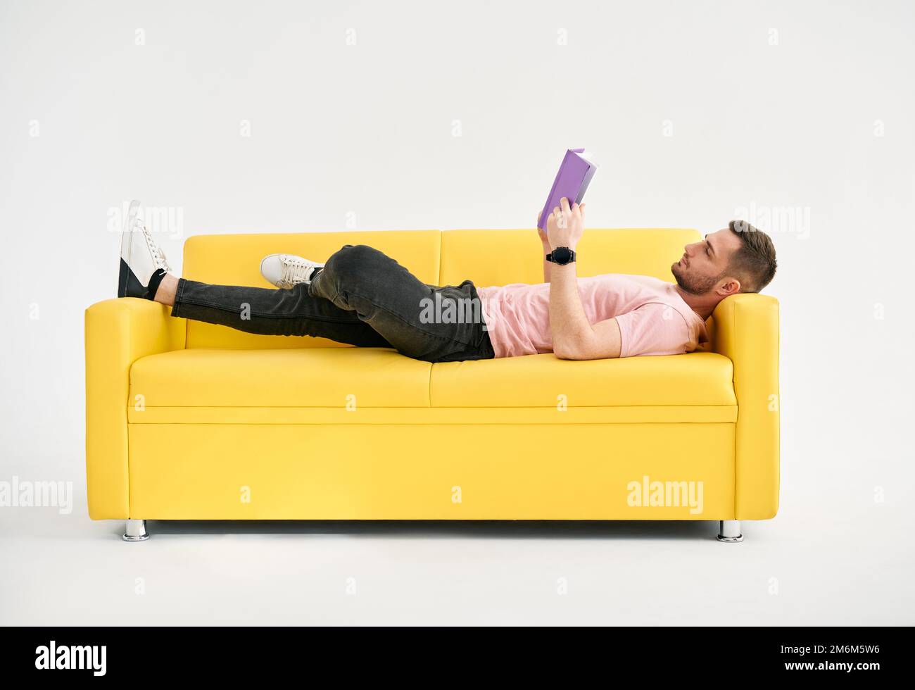 Man relaxing on sofa reading book Stock Photo