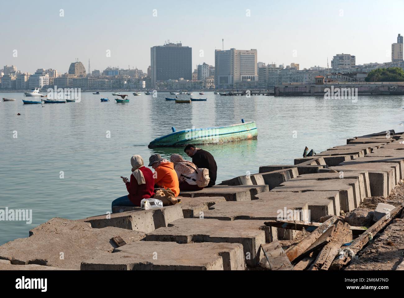 Alexandria, Egypt. December 1st 2022 People on concrete blocks positioned as a defence against rising sea levels along the Corniche of Alexandria, the Stock Photo