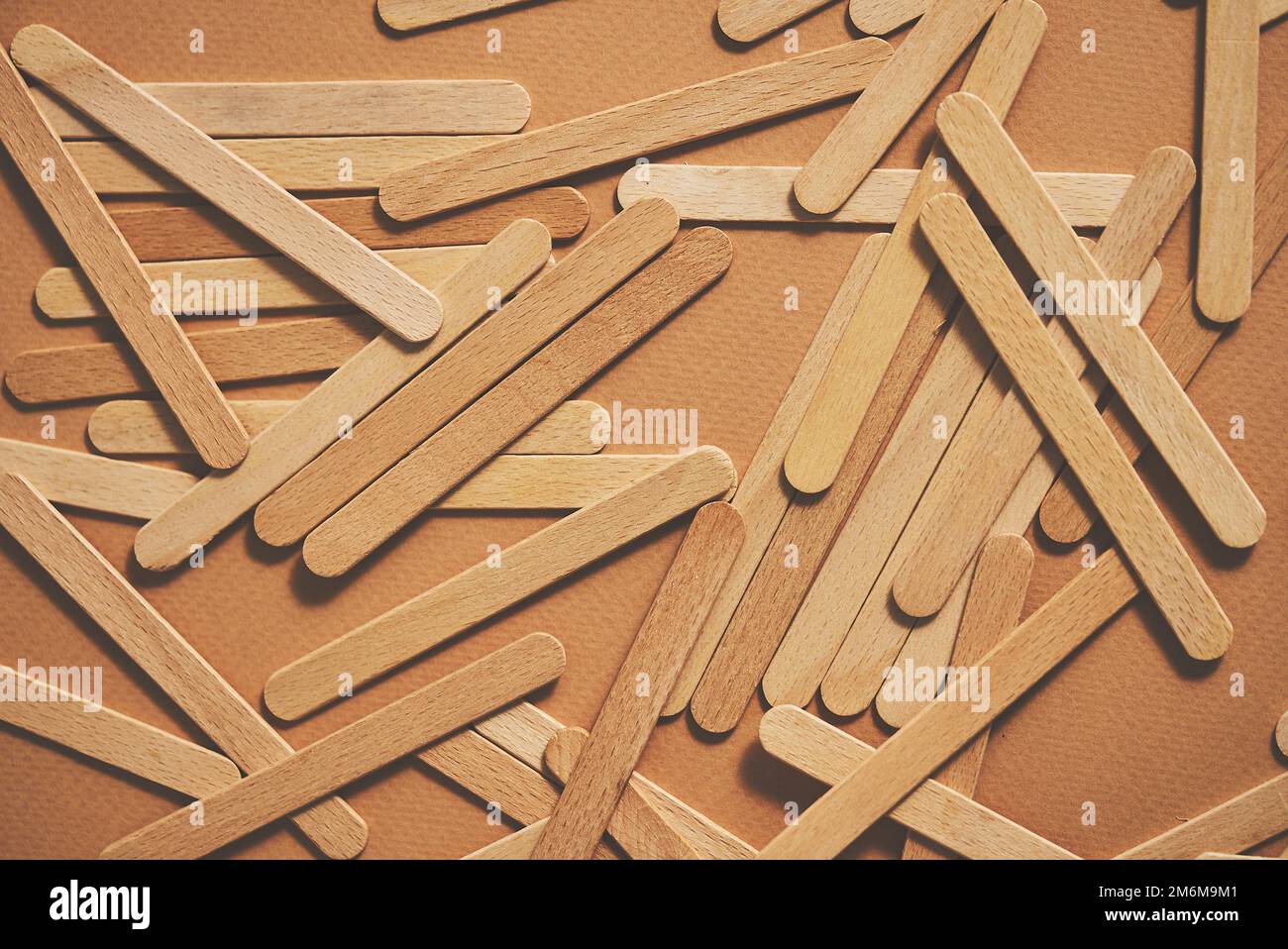 https://c8.alamy.com/comp/2M6M9M1/wooden-popsicle-sticks-scattered-on-top-of-a-beige-background-2M6M9M1.jpg