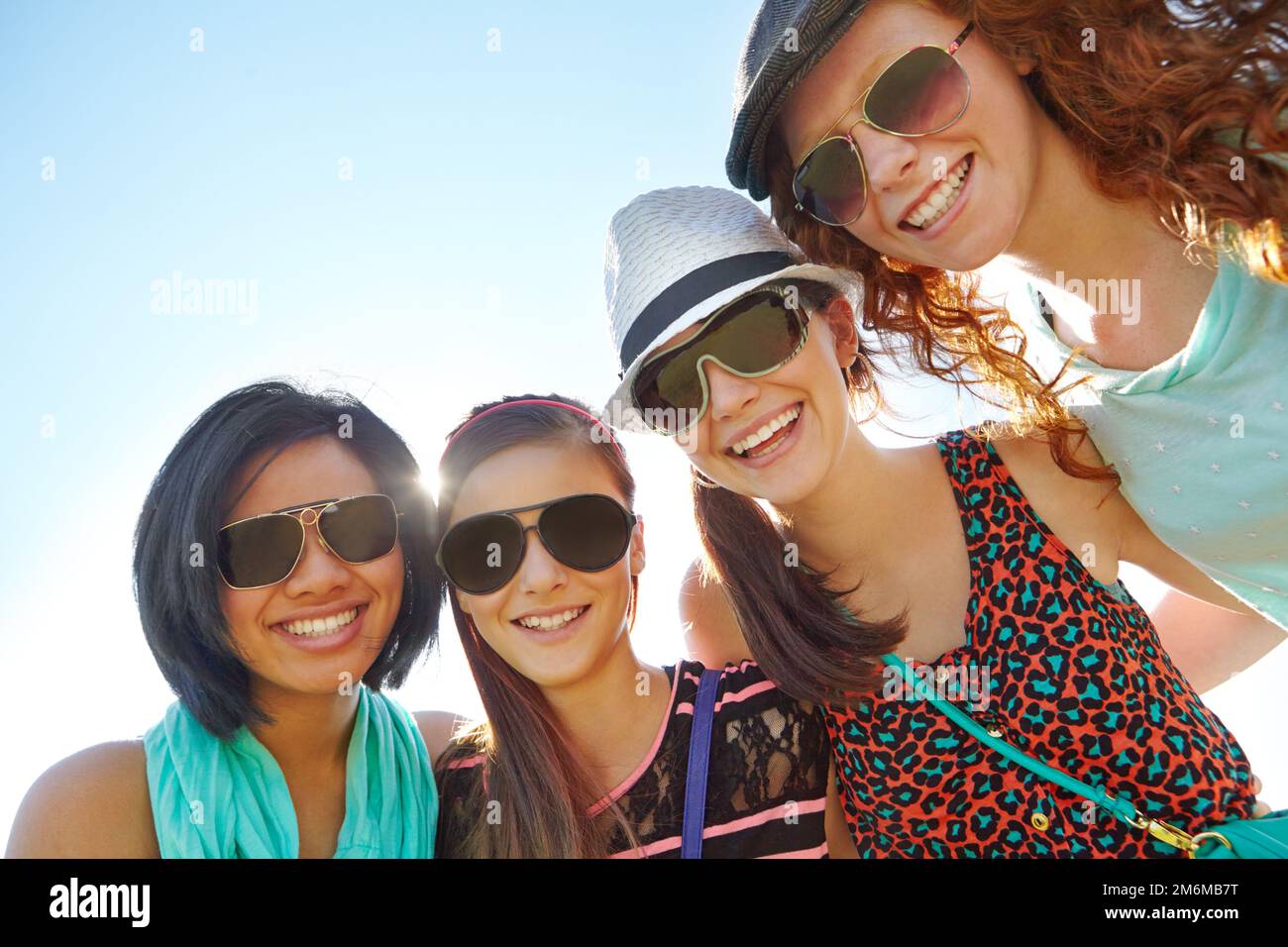 Spending a day with the girls. A group of four teenage girls smiling with their arms around each others shoulders. Stock Photo