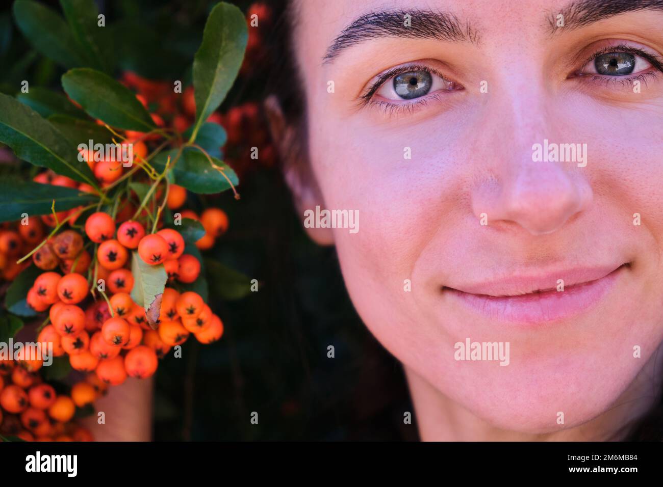 close face eyes portrait Beautiful girl Young woman orange berries Pyracantha Stock Photo