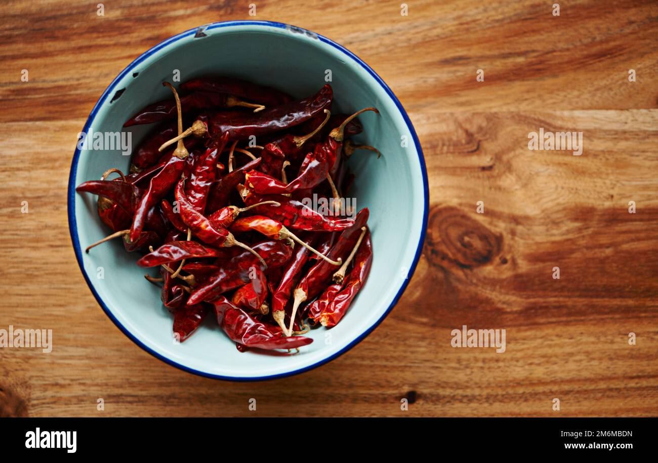 Intensely spicy. High angle shot of dried red chillies in a bowl on a kitchen counter. Stock Photo