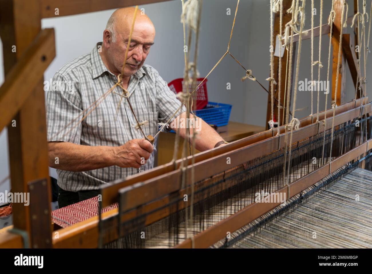 Master craftsman working on a traditional wooden loom and hand weaving