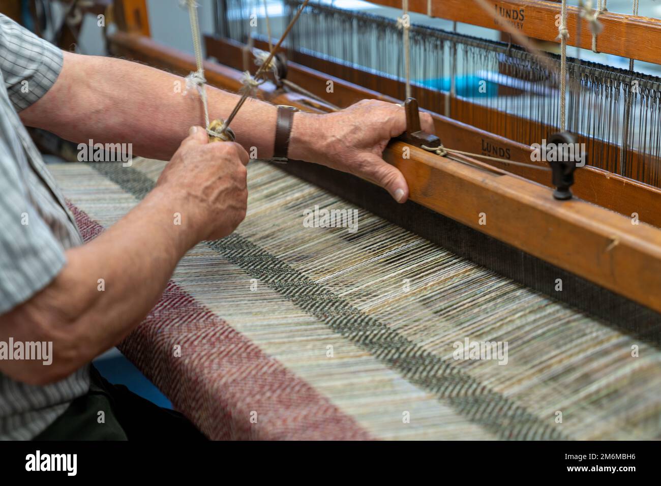 Master craftsman working on a traditional wooden loom and hand weaving