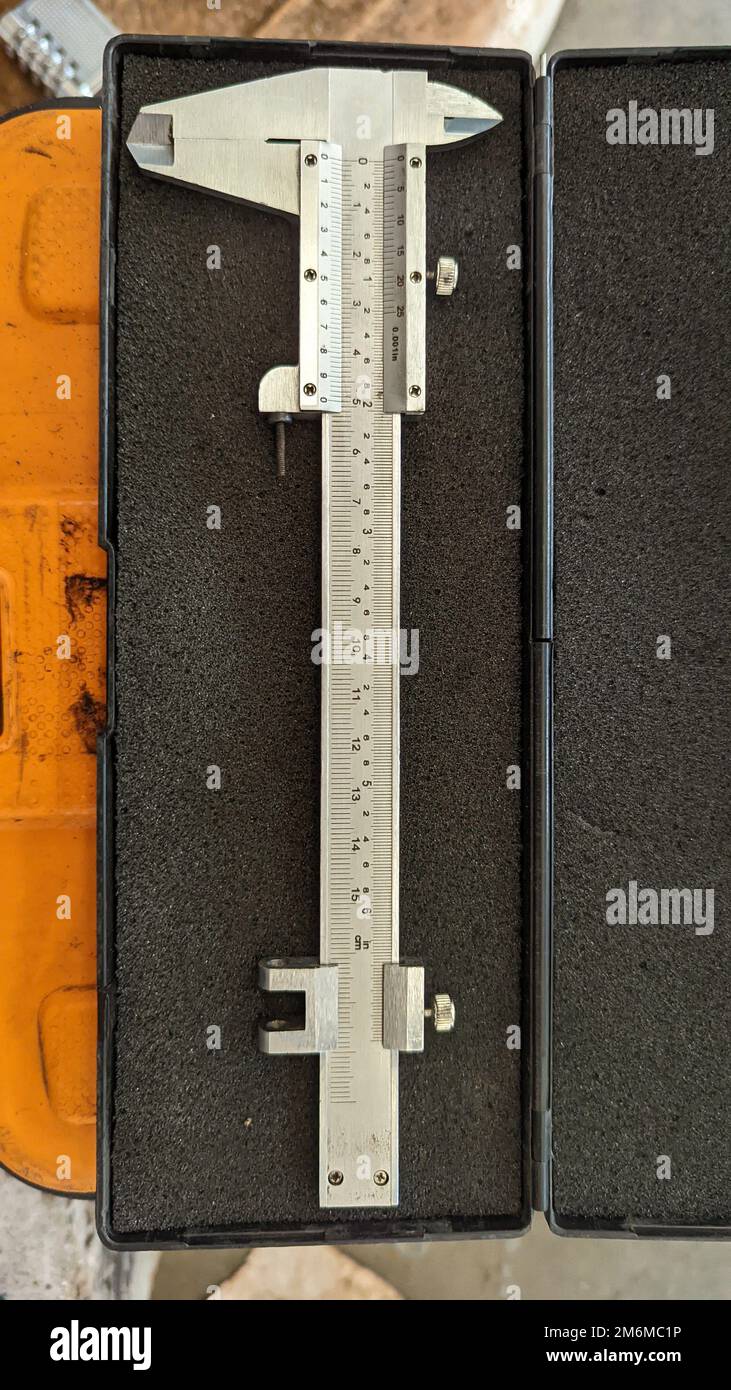 vertical shot of a stainless steel analog vernier caliper scale tool used for precision measurements placed in a black box Stock Photo