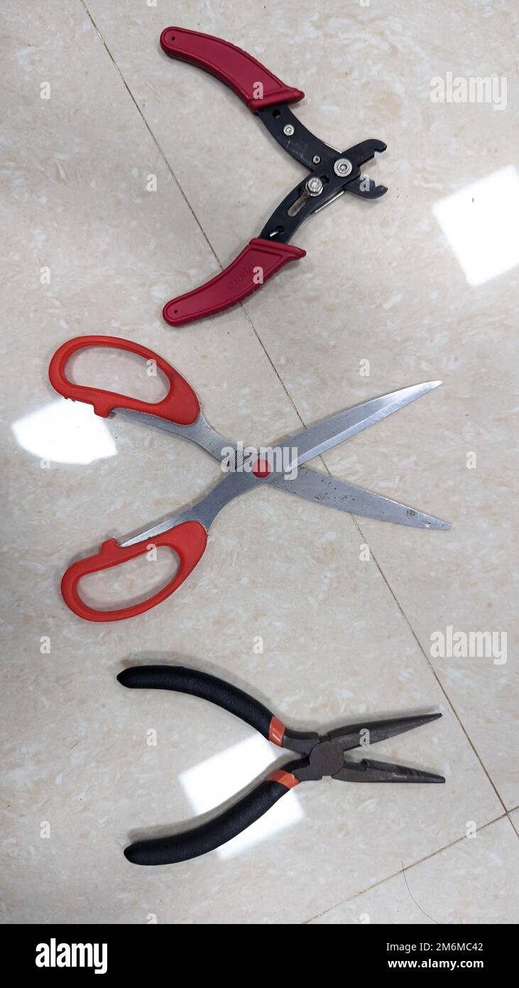 various cutting tools like scissor, cutting plier and wire stripper used in the electronics lab placed on a white floor Stock Photo