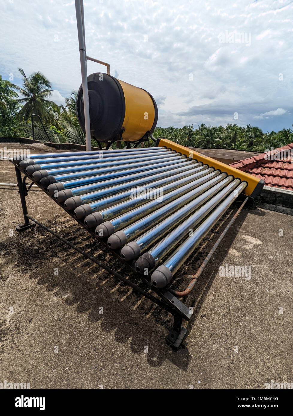 an eco friendly solar water heater and tank installed on the roof of a building for generating hot water renewably Stock Photo