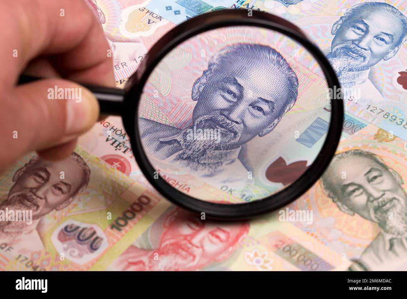 Vietnamese money in a magnifying glass a business background Stock