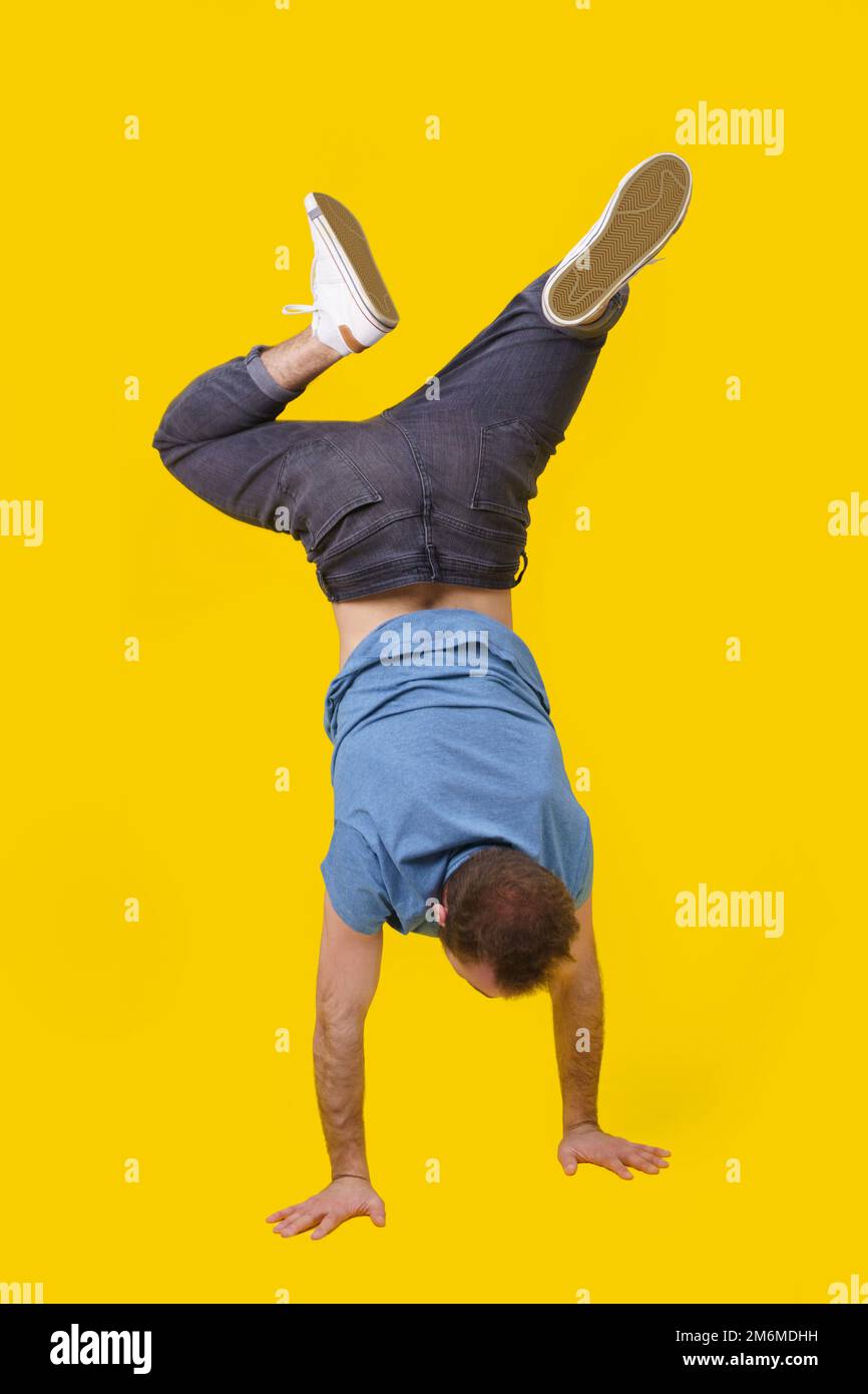 Up side down young man in casual wear standing back on camera posing on yellow background. Stylish look hipster man. Athletic yo Stock Photo