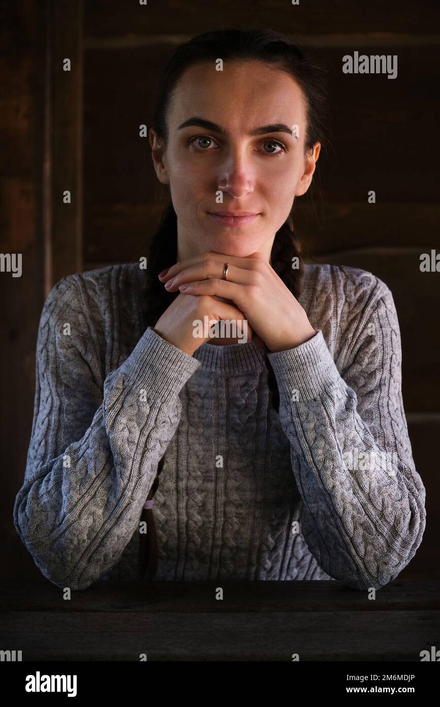 pretty crisp young girl keeps hands under chin glad expression wood background  Stock Photo