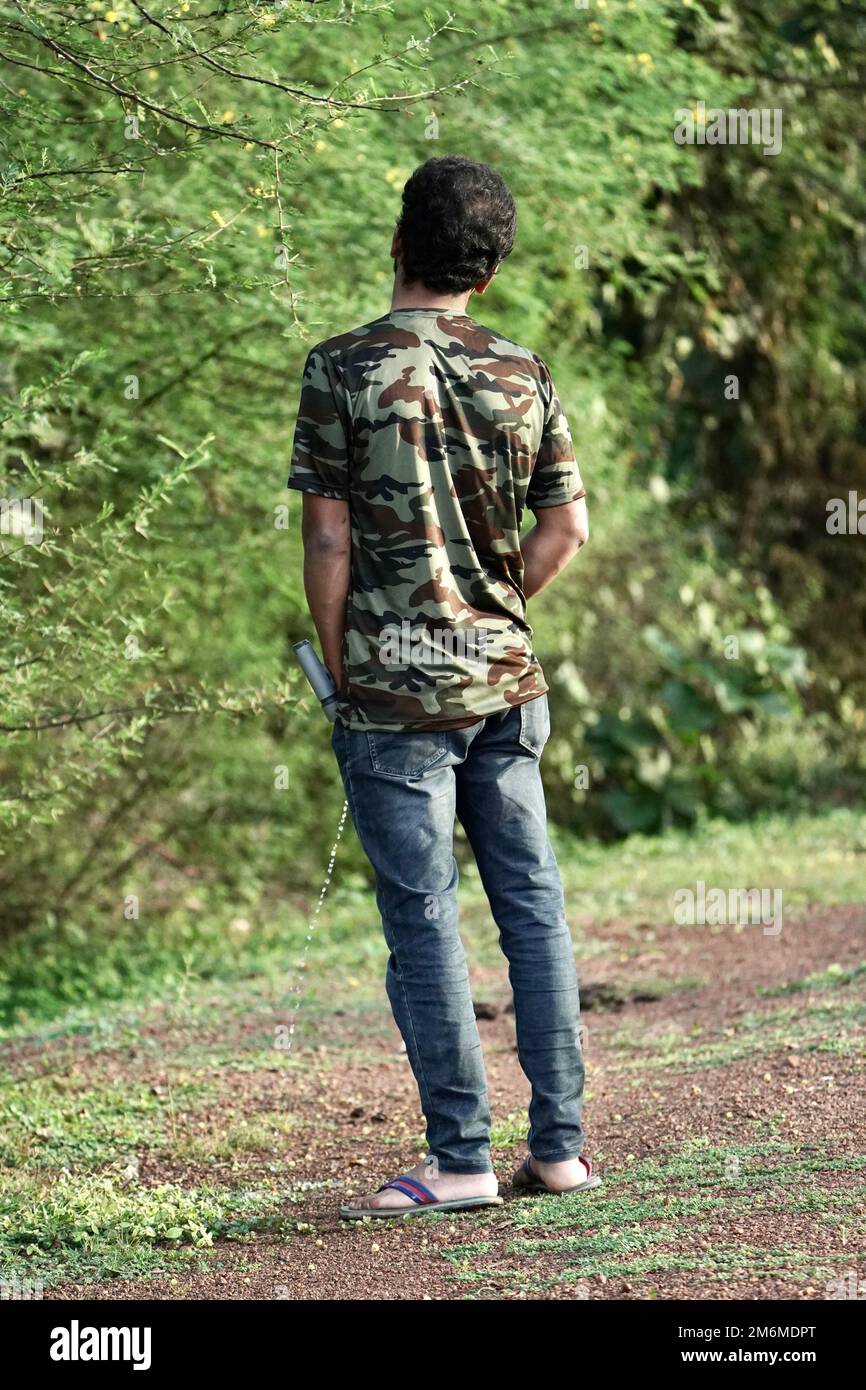 An indian man standing peeing outdoor near side of the road, outdoor,  urinary problem concept, A man in blue jean is urinating or pissing outdoor  in g Stock Photo - Alamy