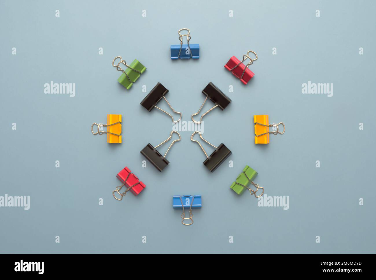 Circle of colorful binder clips against a light blue background Stock