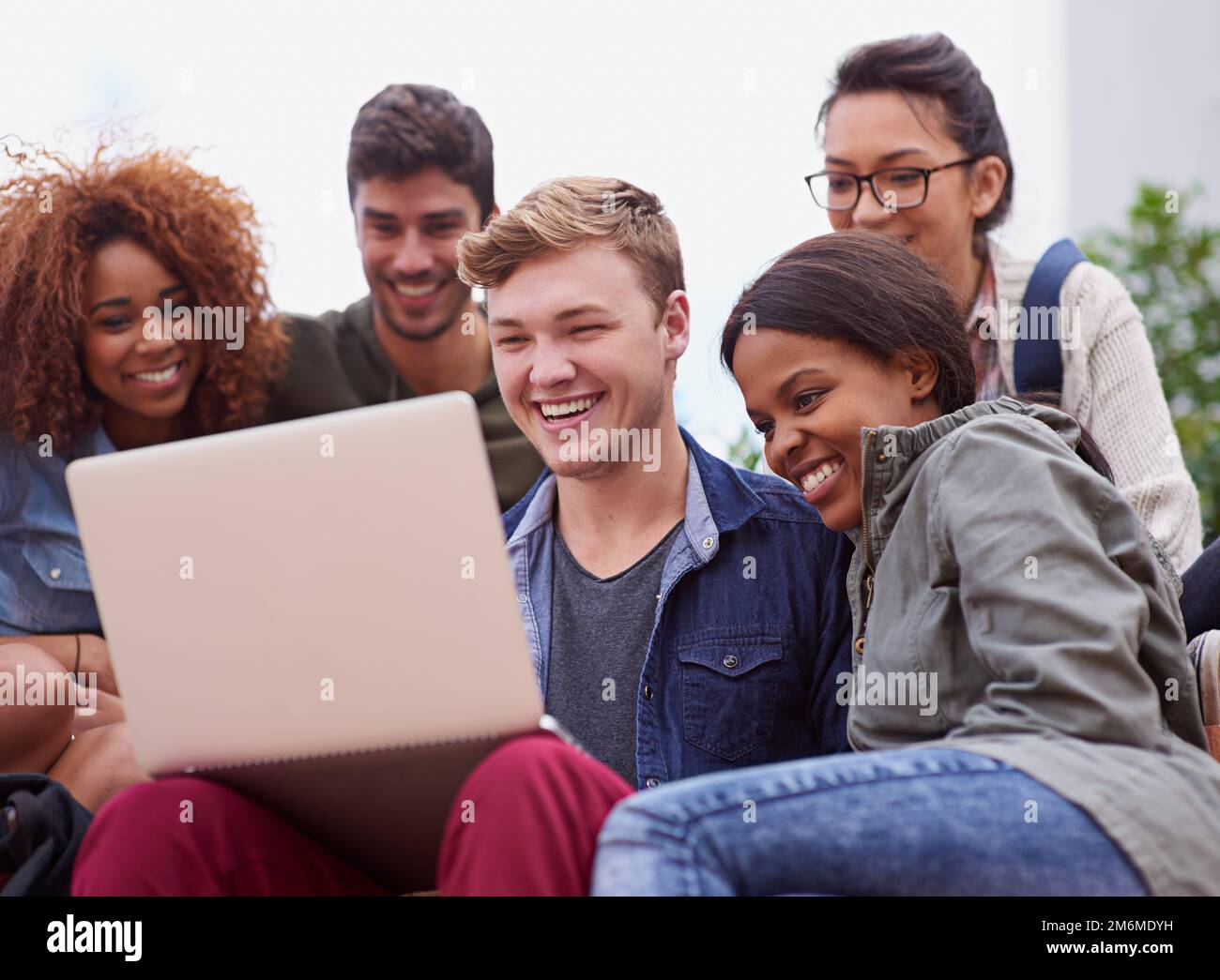 Your answer is a click away. a group of students sitting outside while on campus. Stock Photo