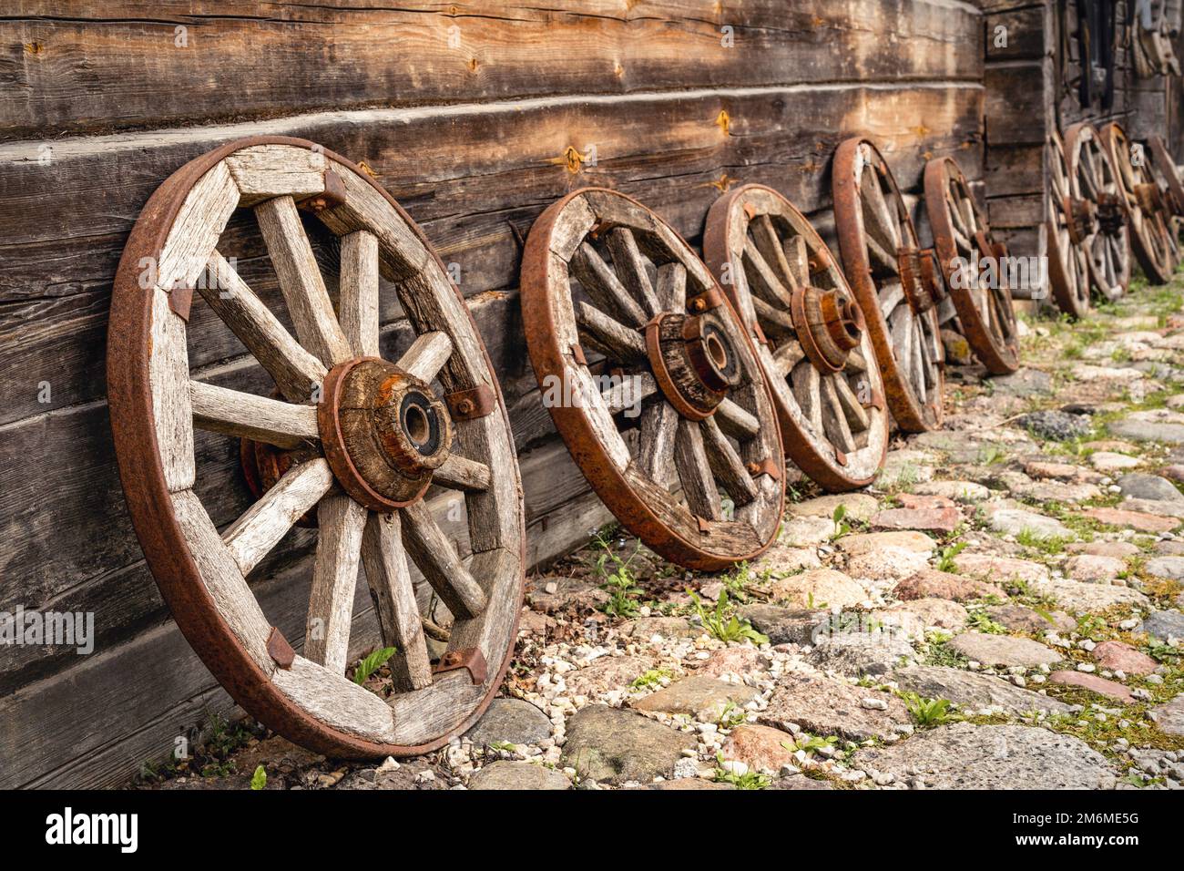 Old wooden wagon wheels leaning on a log cabin Stock Photo Alamy