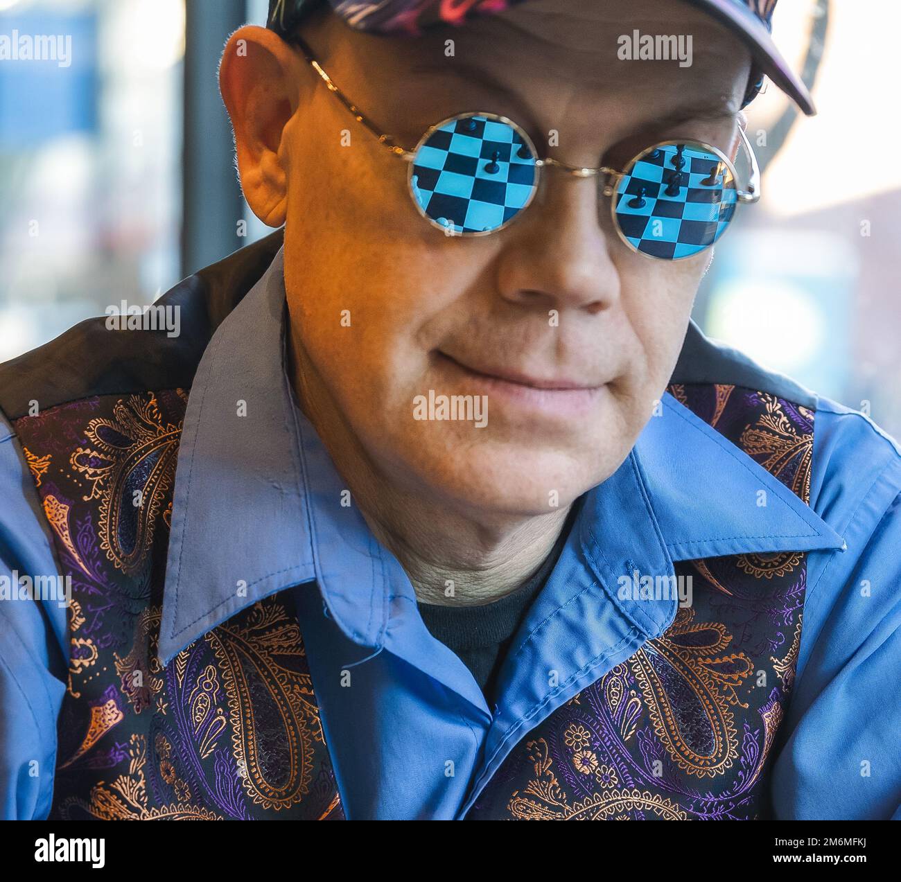 A man with indoor sunglasses reflecting a chess game Stock Photo