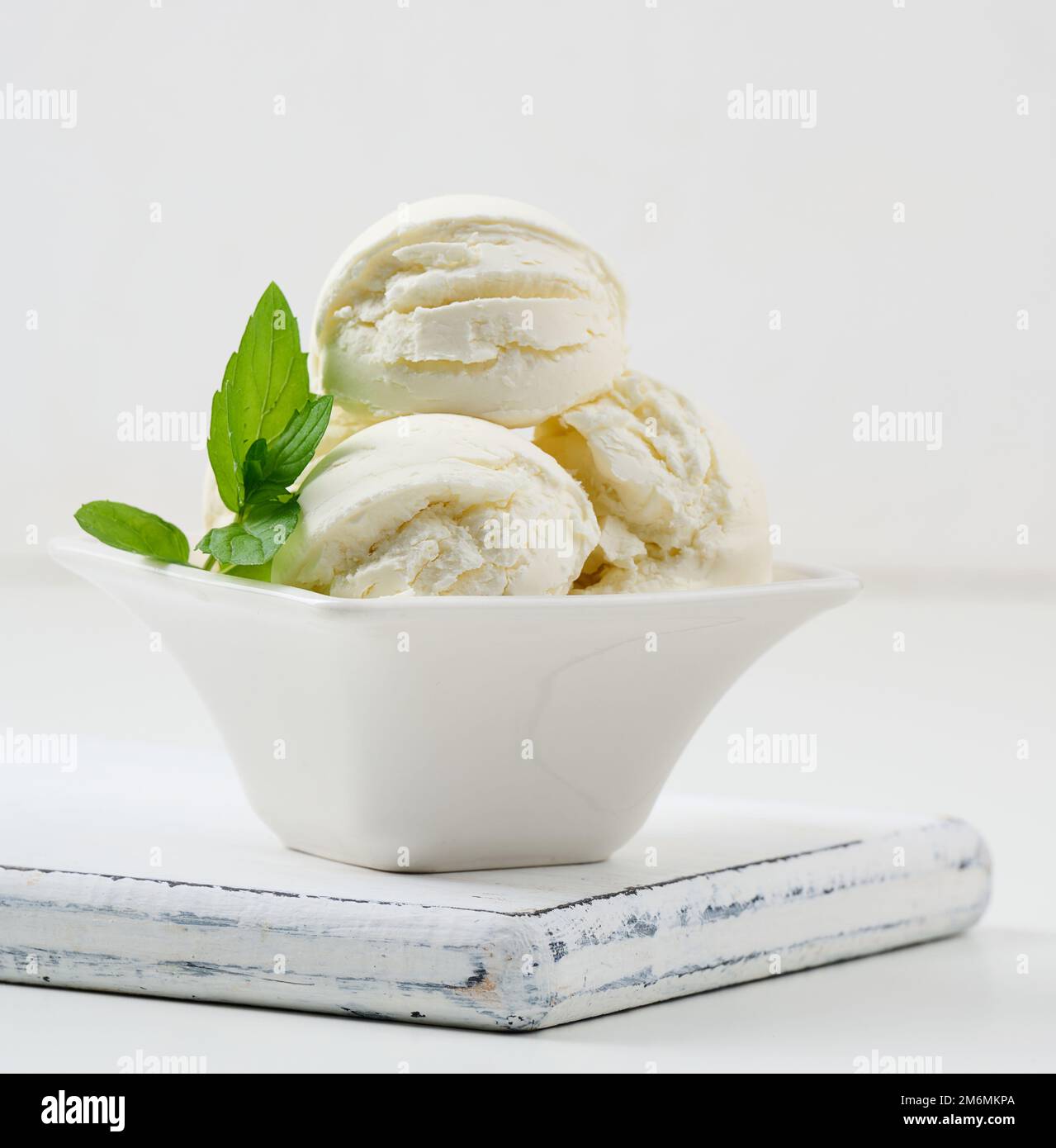 Vanilla ice cream balls with green mint leaf in a white ceramic plate Stock Photo