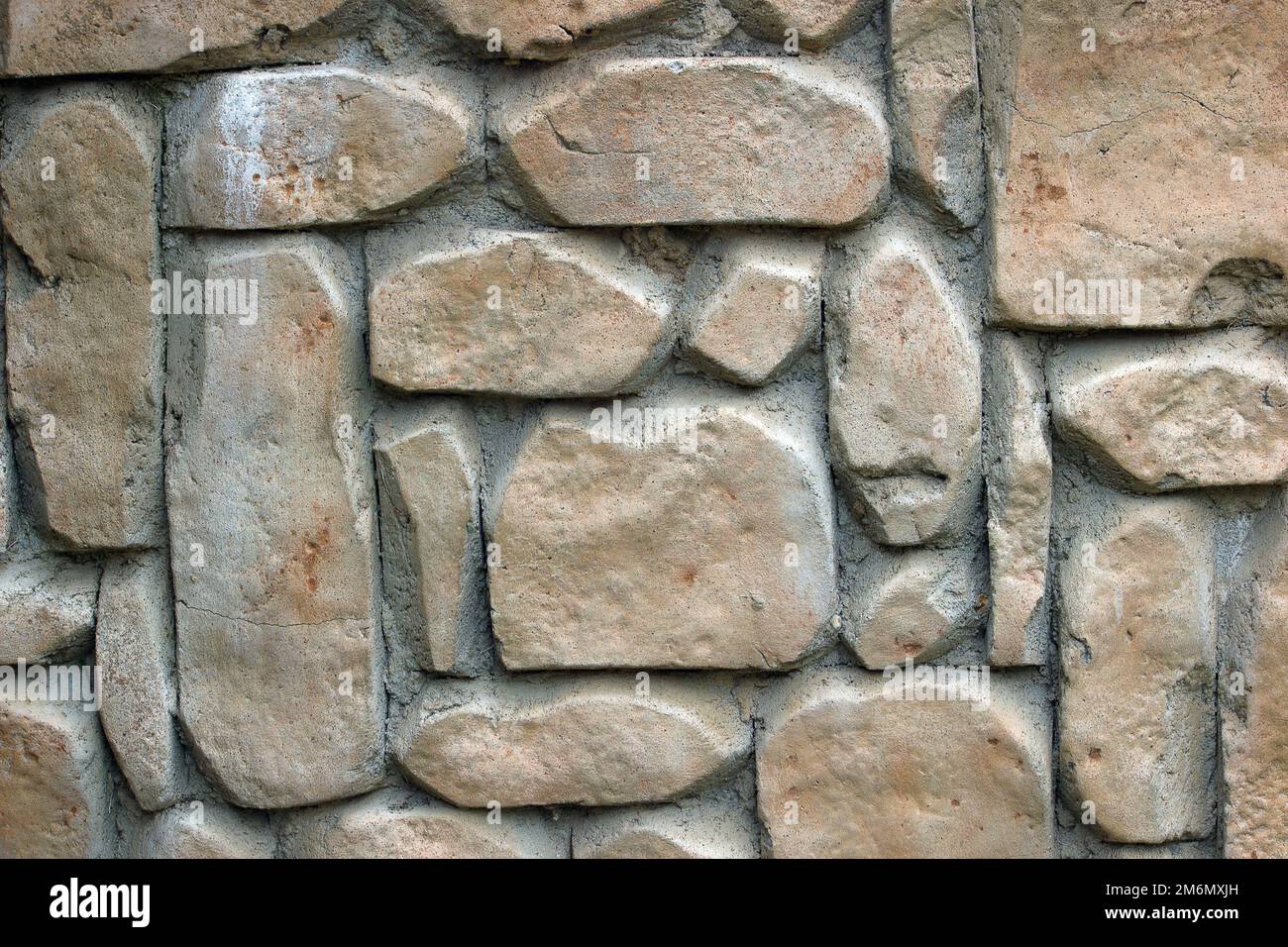 Light brown stones of varying sizes built into a wall, can be used as background Stock Photo