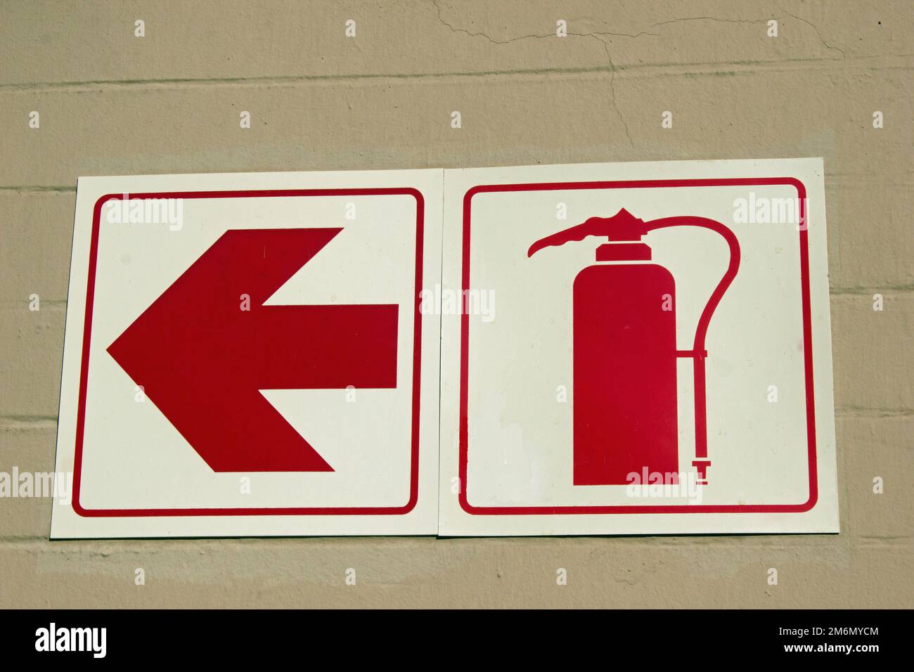 Red signs on white against a wall showing where fireextinguisher can