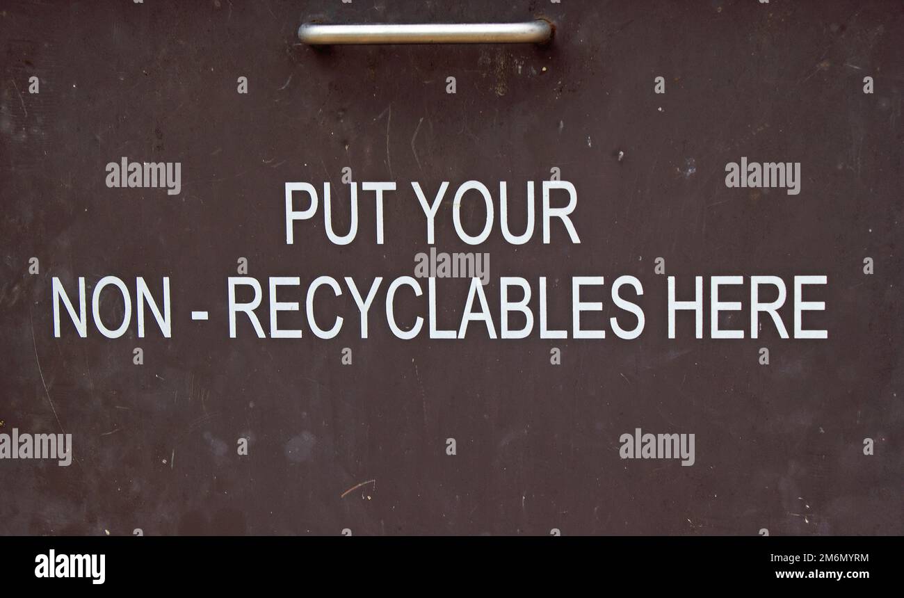 white lettering, dark background on metal bin with instruction to put nonrecyclable items in