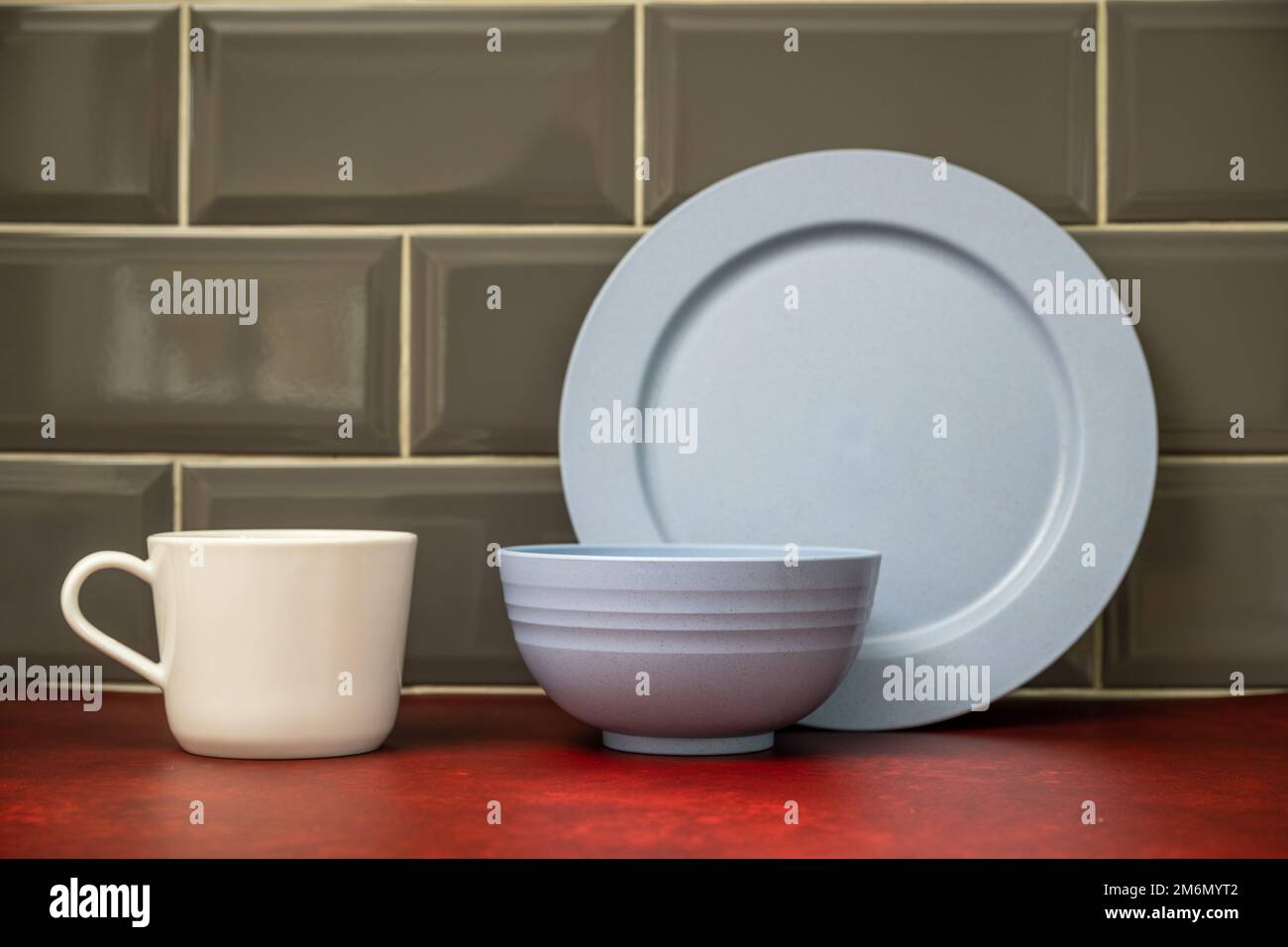 blue   dinner plate bowl with white china cup stacked in the kitchen on a red linoleum work top Stock Photo