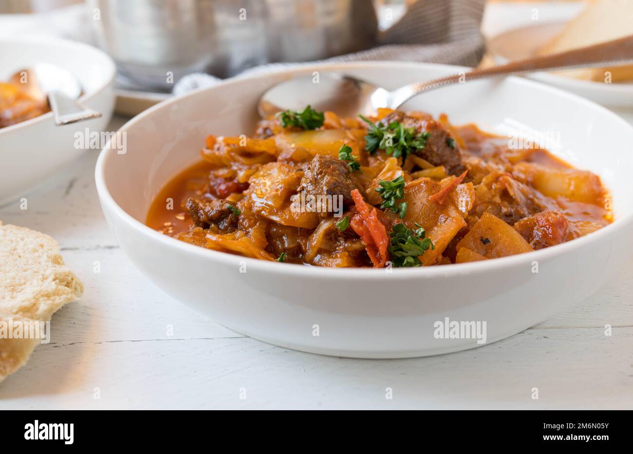 Beef stew with cabbage and vegetables in a bowl on kitchen table