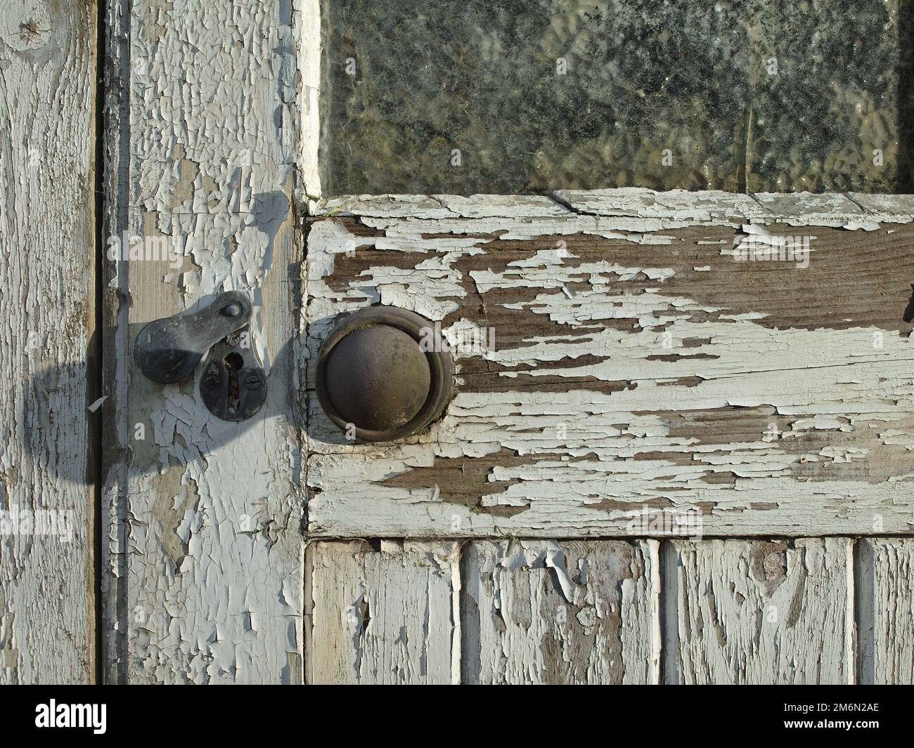 close up of an old white door with peeling paint on a building in a yard Stock Photo