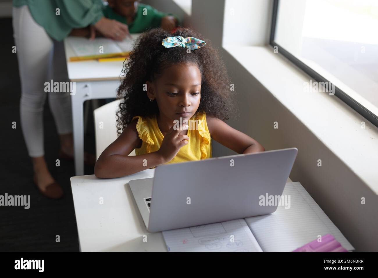 African american elementary schoolgirl using laptop at desk in ...