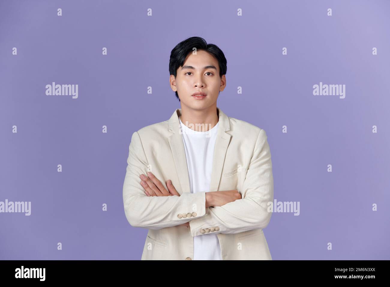 Smiling young Asian businessman in beige suit isolated on purple background Stock Photo