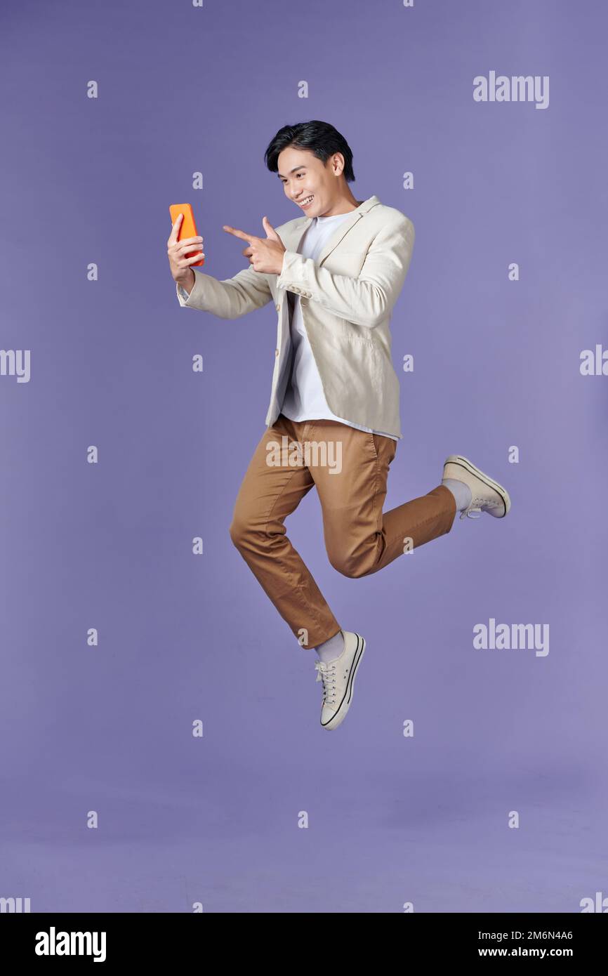 image of jumping up asian man holding smartphone in hand Stock Photo