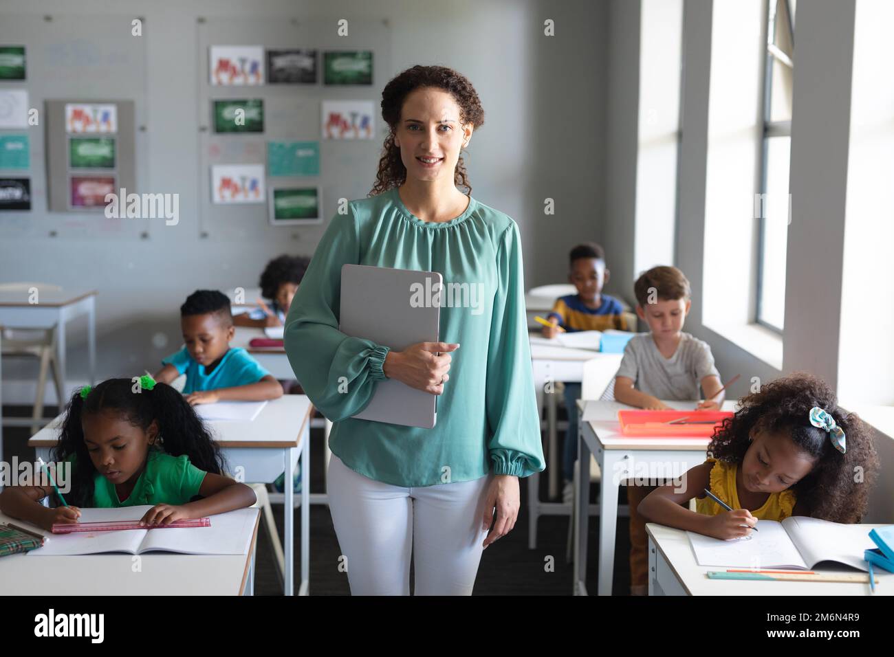 Portrait of caucasian young female teacher standing by multiracial ...