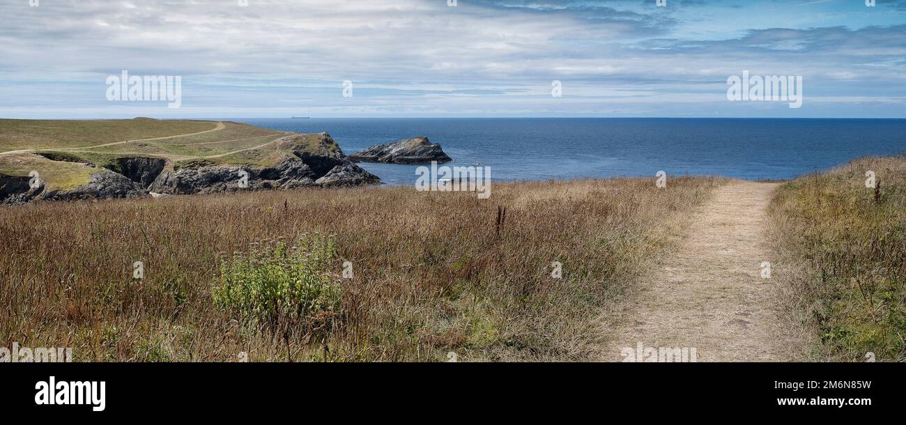 A panoramic image of a rough footpath through a field on West Pentire on the coast at Newquay in Cornwall in the UK. Stock Photo